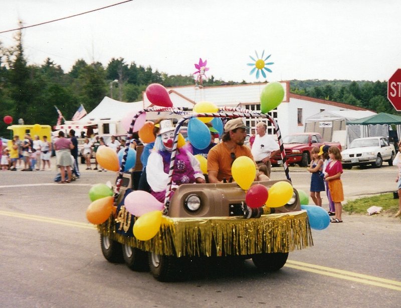 clowns riding in a balloon covered six-wheel car