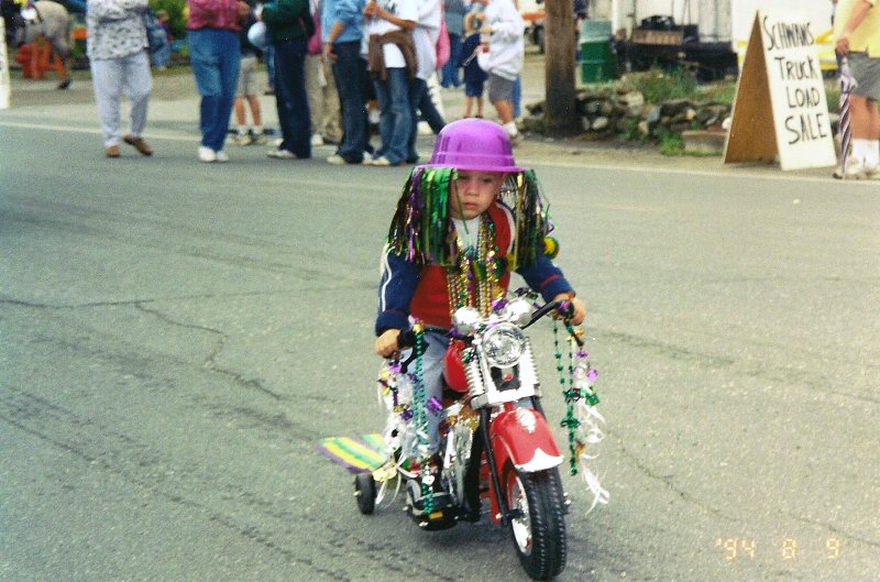 child dressed in mardi gras costume on mini bike