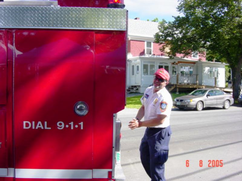 smiling fire fighter walking behind fire truck