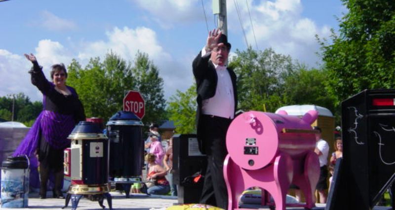 man dressed in top hat and tails and lady in purple dress waving from float